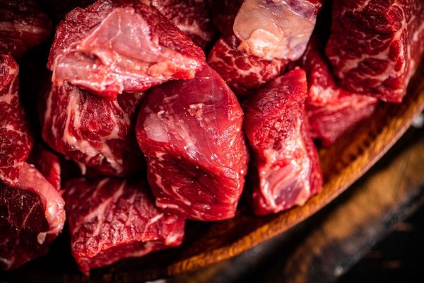 Raw sliced beef in a wood bowl on a dark background