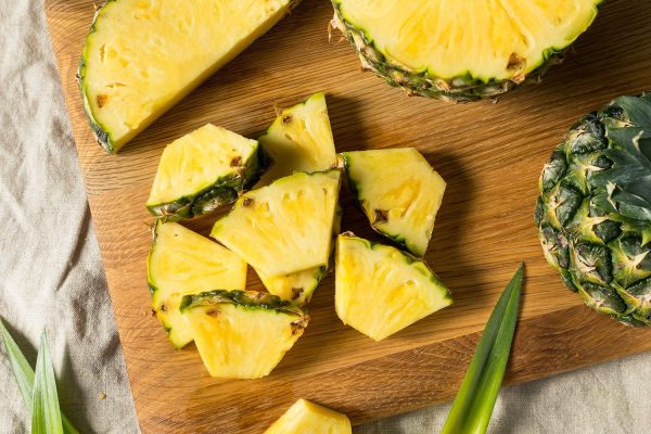 Close up of fresh organic pineapple sliced on a wooden cutting board ready to eat.