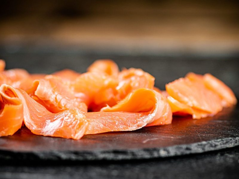 Close up of slices of salted salmon on the table with a wooden background.